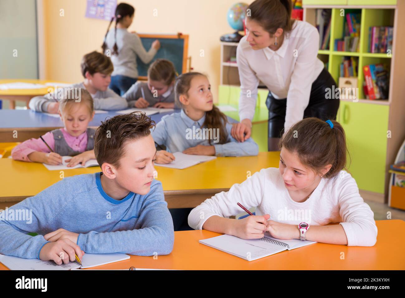 Teacher and pupils working in classroom Stock Photo