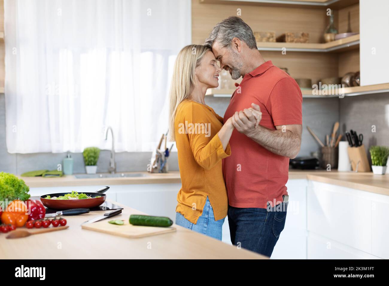 Romantic middle aged couple having fun at kitchen, dancing Stock Photo