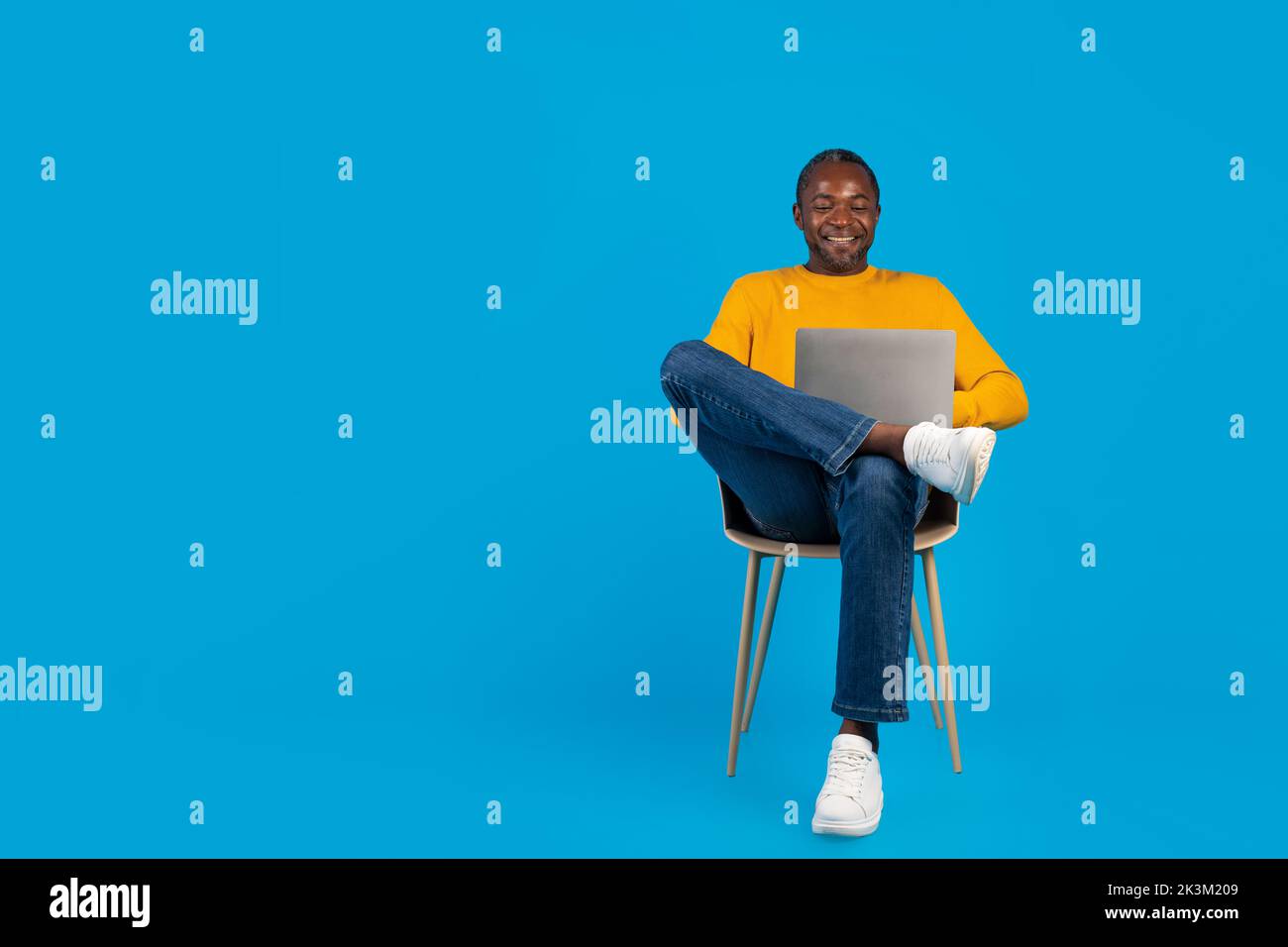 Handsome black man relaxing on chair with computer Stock Photo