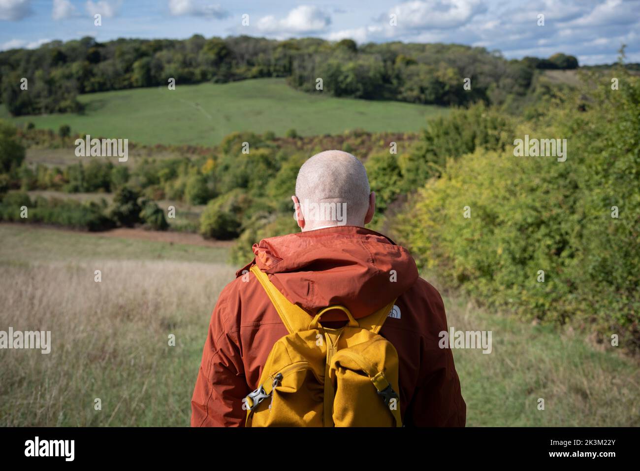 A rear view of a male walker who is following his friends as they descend a hill during a weekend walk in the Kent countryside, on 25th September, in Shoreham, Kent, England. Stock Photo