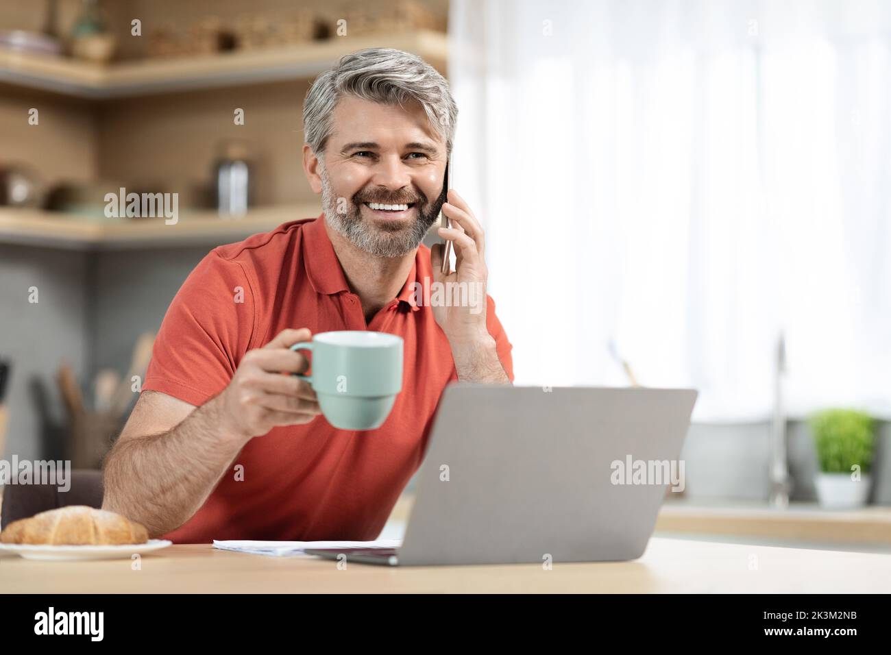Cheerful handsome man drinking coffee and having conversation Stock Photo