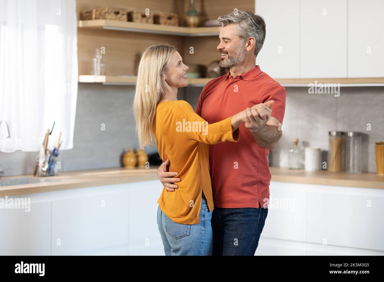Beautiful mature spouses dancing together at kitchen Stock Photo