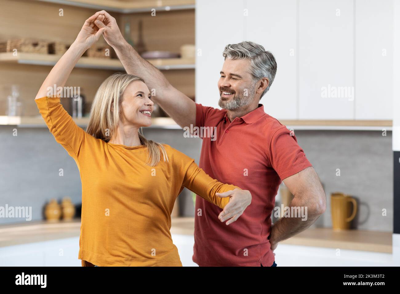 Loving middle aged couple dancing at kitchen Stock Photo