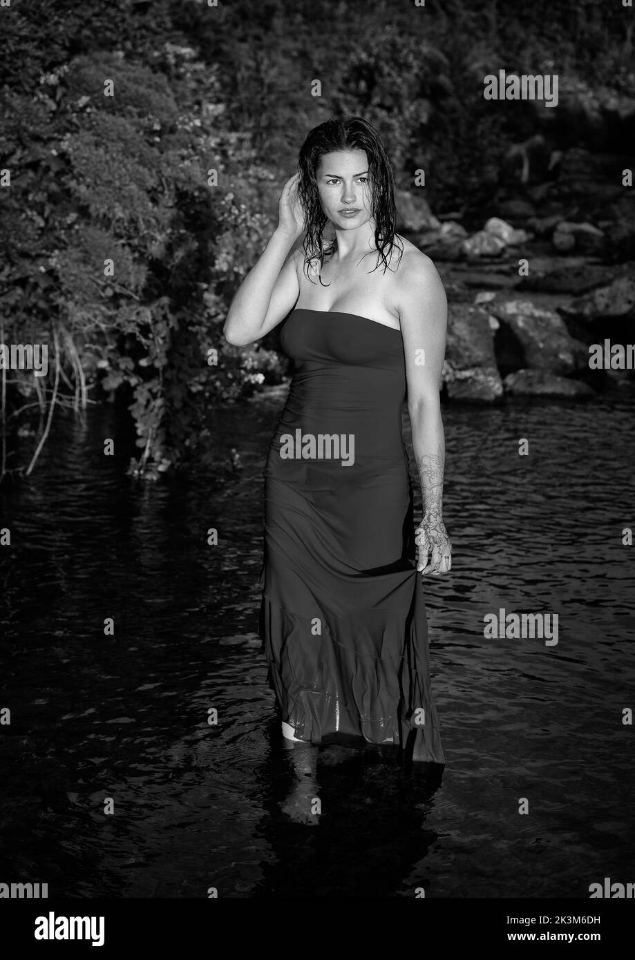 A beautiful woman standing in water in black and white Stock Photo