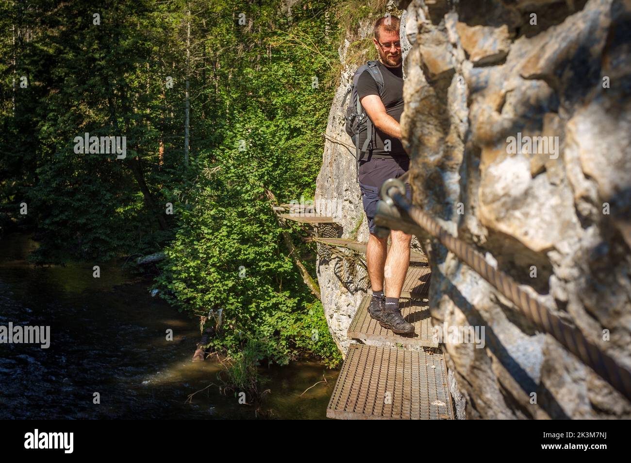 A male tourist walking along iron walkway over the river Hornad in Prielom Hornadu in Slovak Paradise, Slovakia Stock Photo