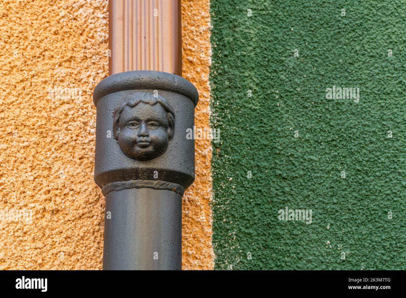 A closeup of metal face sculpture in background of wall Stock Photo