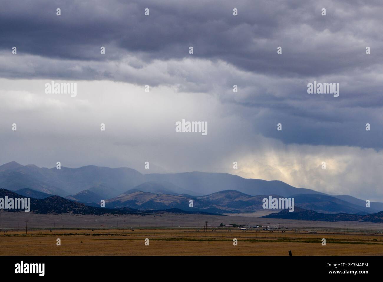 Storm clouds drop rain over the distant mountains in the high desert near Moffat in Colorado USA Stock Photo