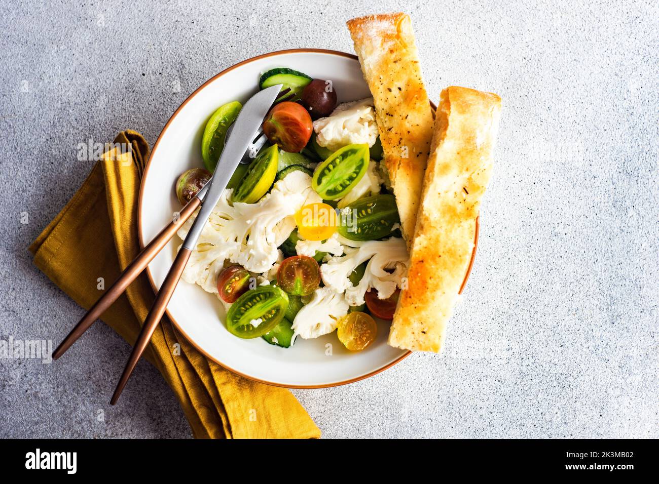 Healthy vegetable salad in the bowl and fresh baked focaccia bread served on concrete table Stock Photo