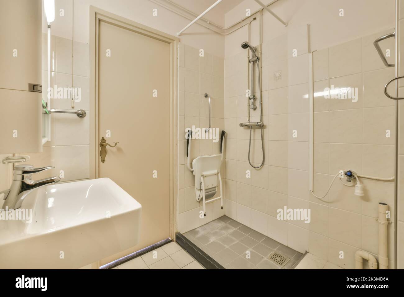 Interior of modern disabled shower cabin with tiled walls and chrome