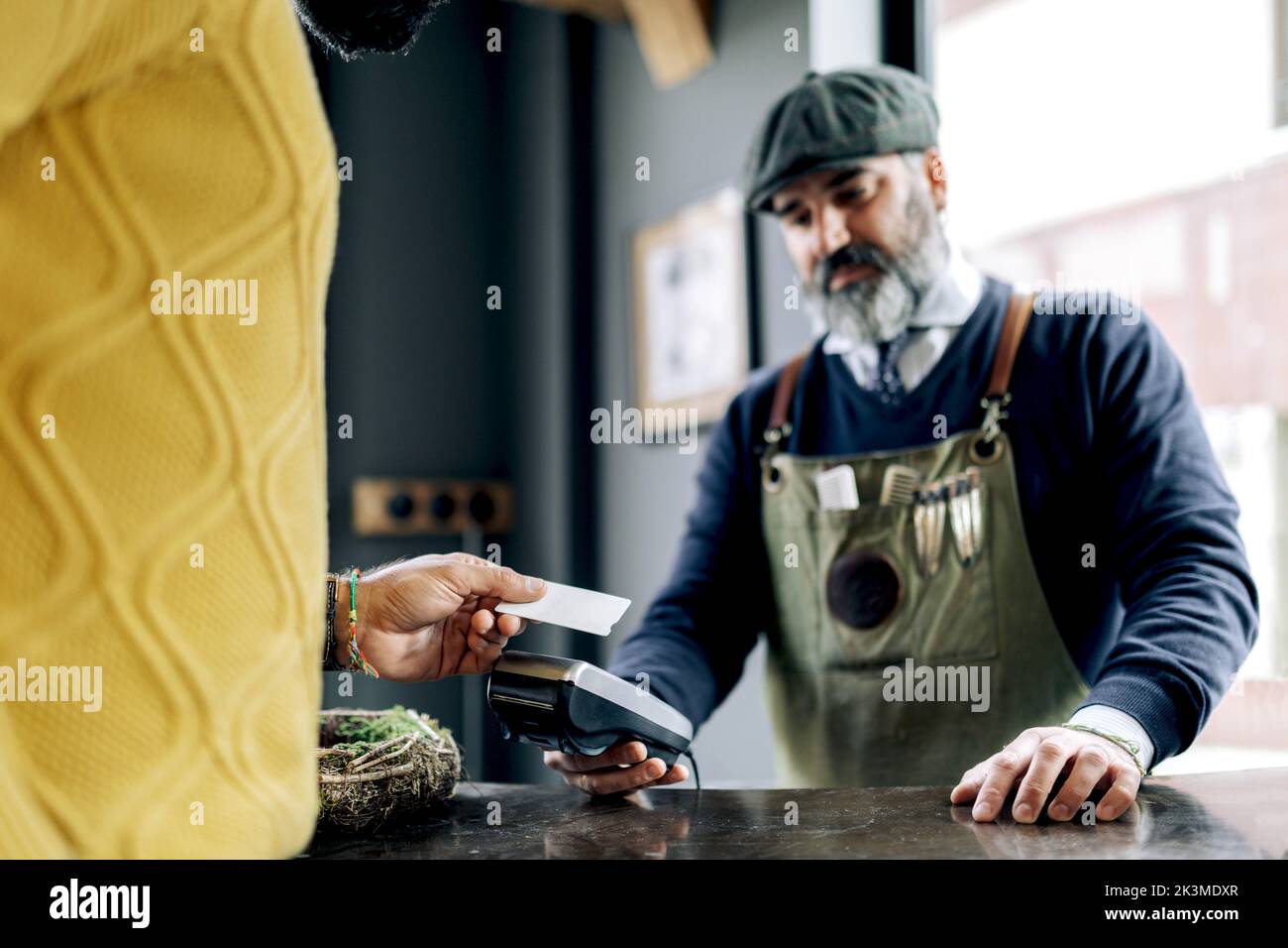 Picture of Crop male customer making payment for hairstyle with plastic card on ...