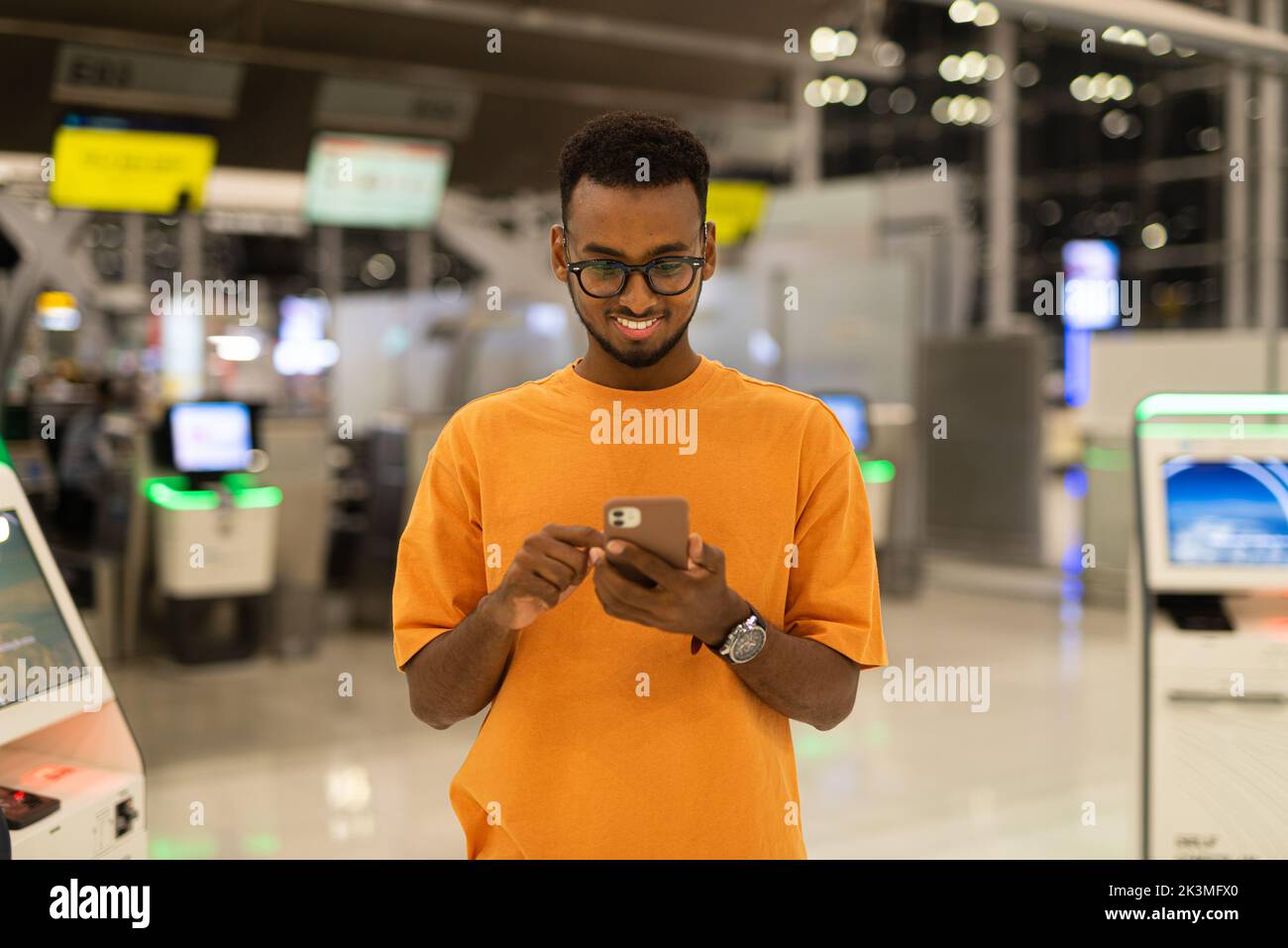 Young handsome black man ready to travel at airport terminal waiting for flight while using phone Stock Photo