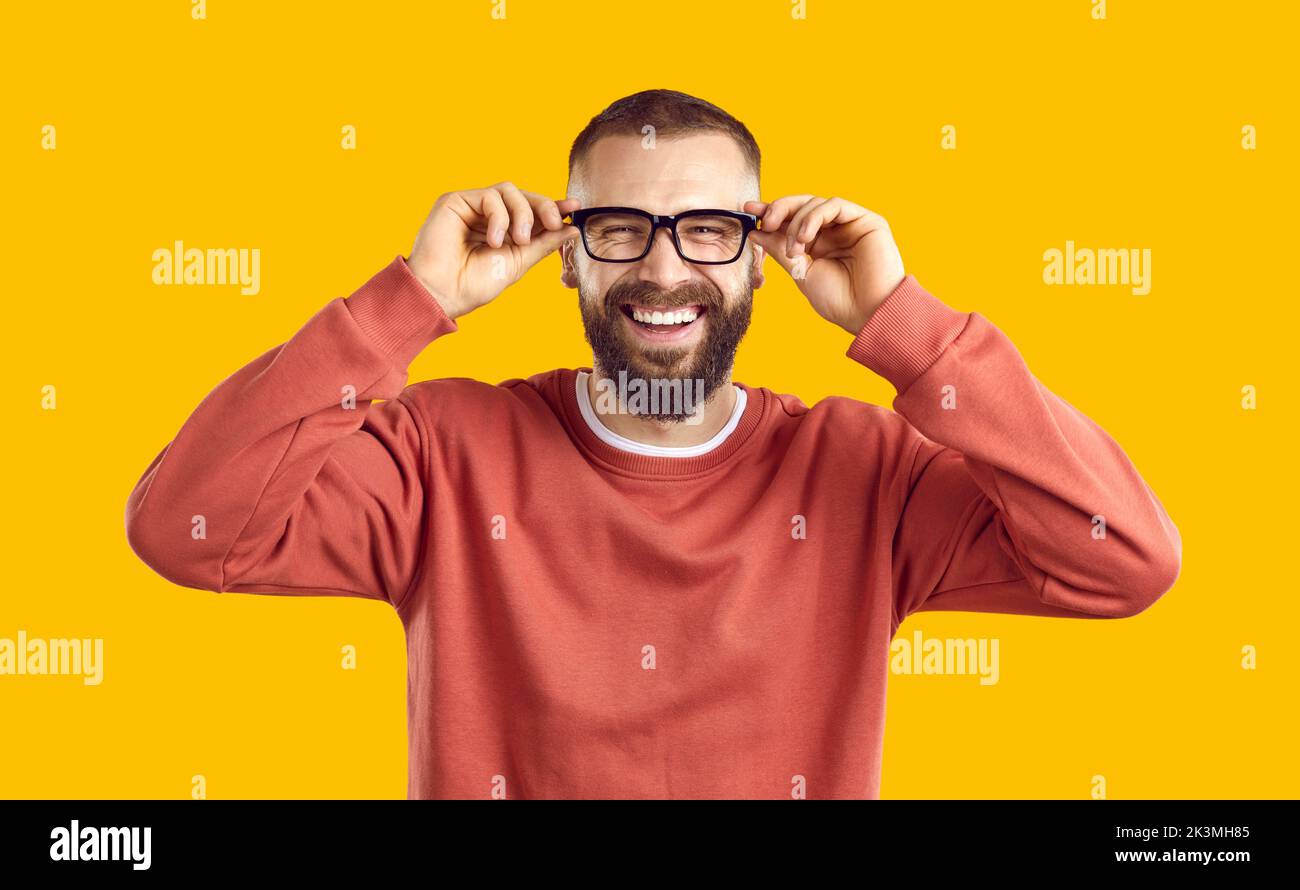 Happy cheerful bearded man in glasses standing on yellow background and laughing Stock Photo