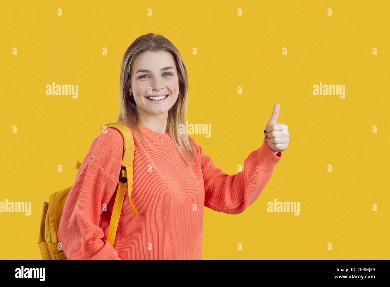 Happy caucasian student girl showing ok and excellent sign isolated on bright yellow background. Stock Photo