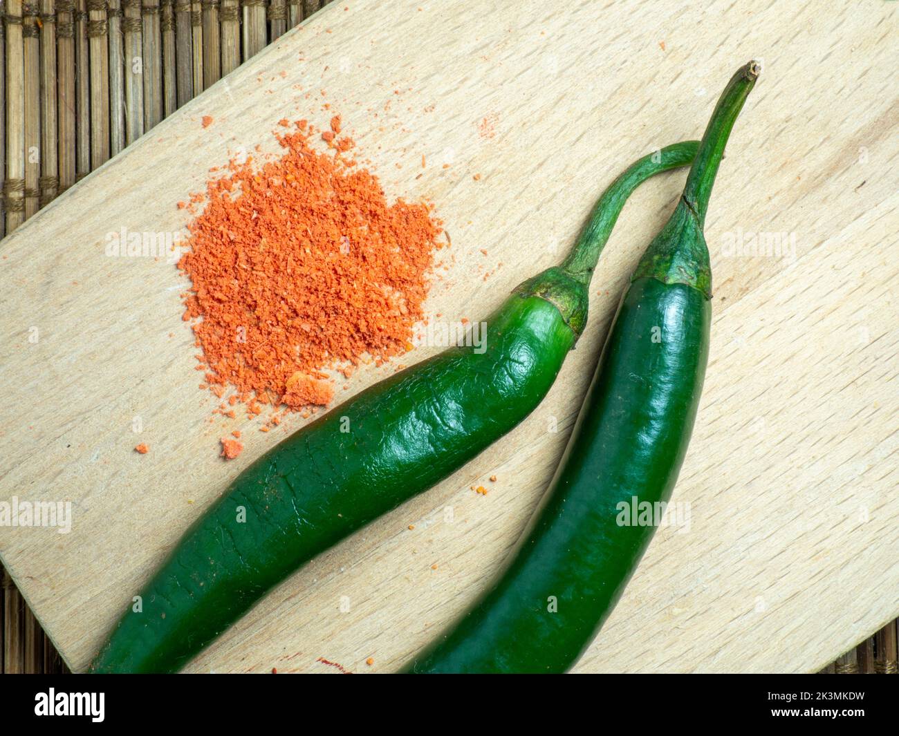 Green chili and ground red pepper on a cutting board. Green spicy chili