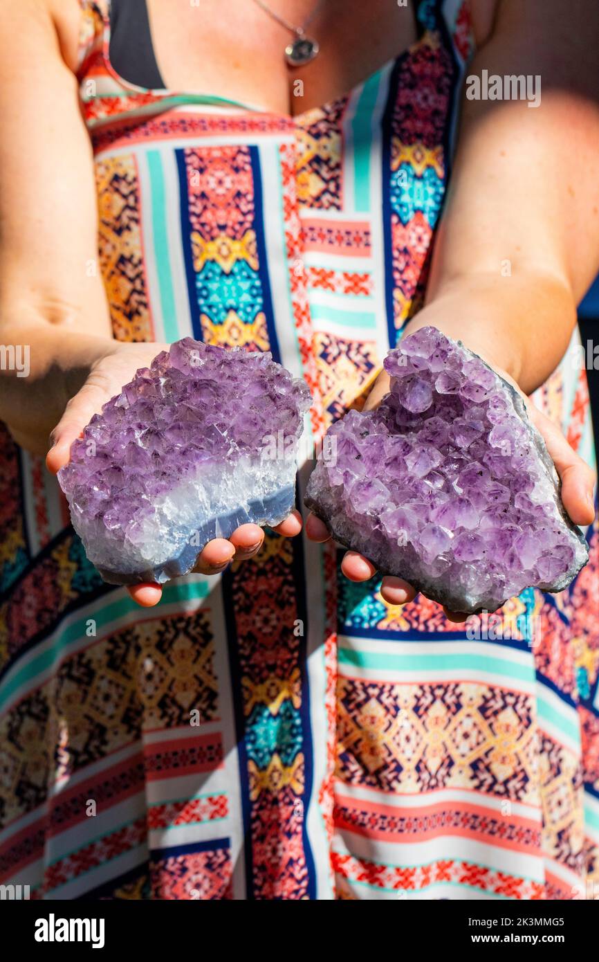 A vertical closeup shot of hands holding beautiful purple amethyst mineral rocks Stock Photo