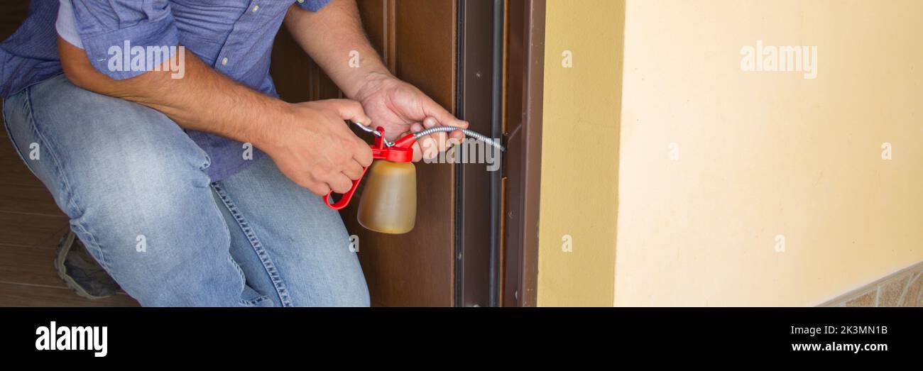 Picture of a handyman who with an oiler lubricates the hinges of a