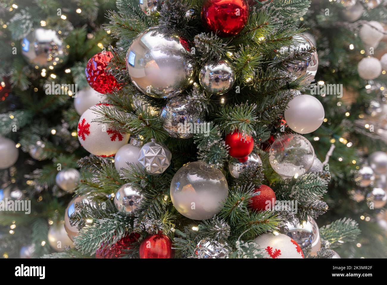 A lightly flocked decorated Christmas tree with various red and silver