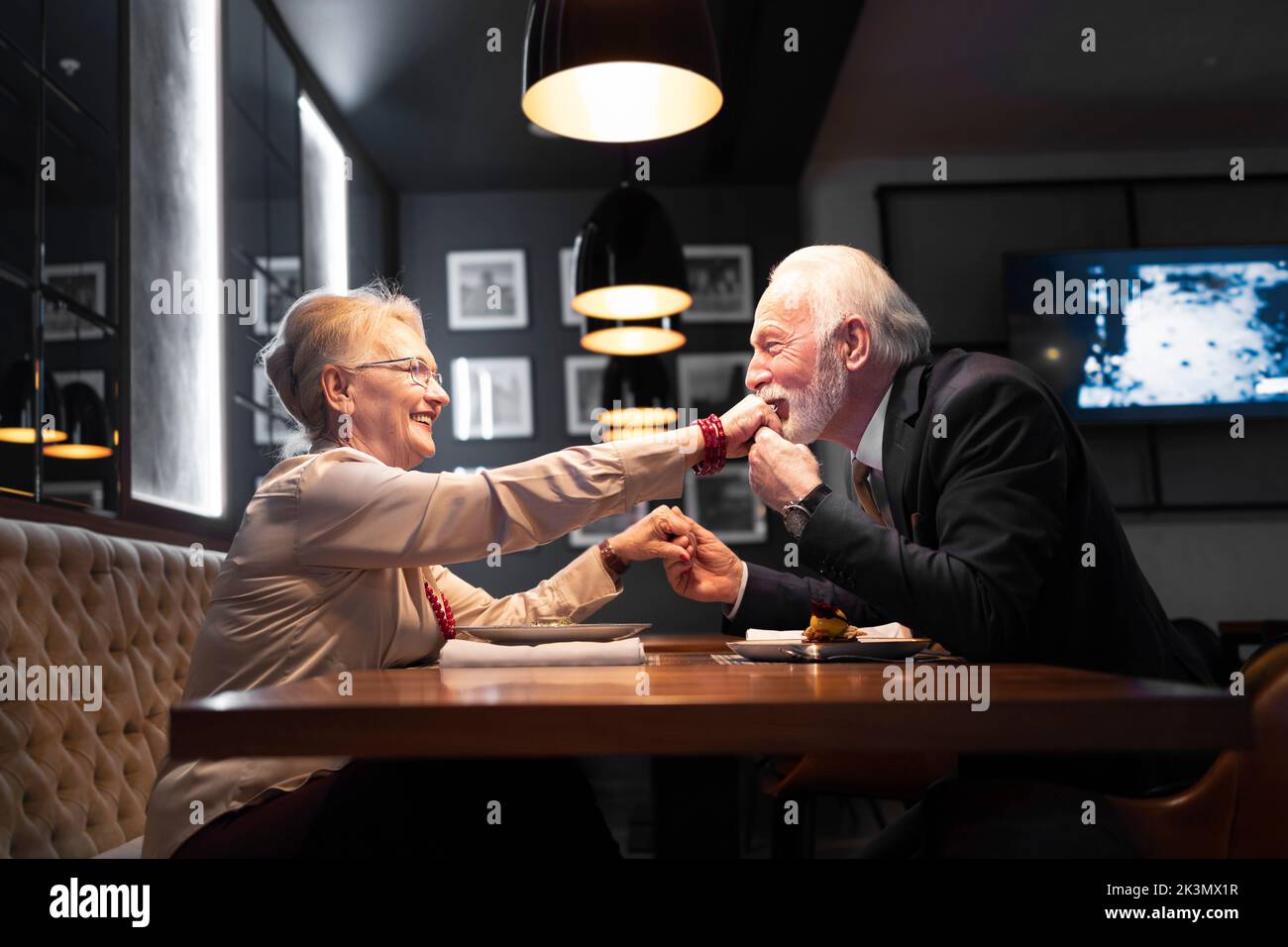 Elderly man kissing a hand of his partner during the Christmas dessert Stock Photo