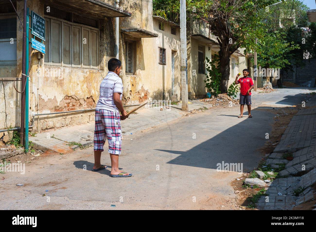 A couple of young boys playing cricket in the street of Bengaluru, India Stock Photo