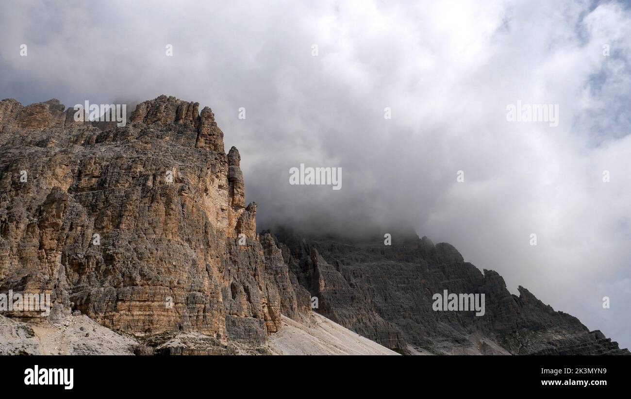 A low-angle shot of dolomite mountains touching the clouds in Trentino, Italy Stock Photo