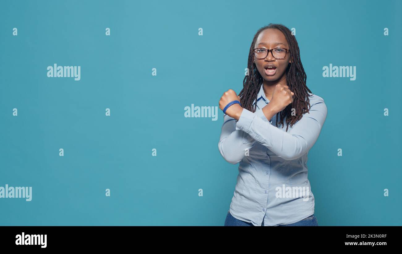 Woman doing stop rejection gesture with arms, standing over blue background in studio. Showing refusal and forbidden symbol with crossed hands, expressing negative emotion and dislike. Stock Photo