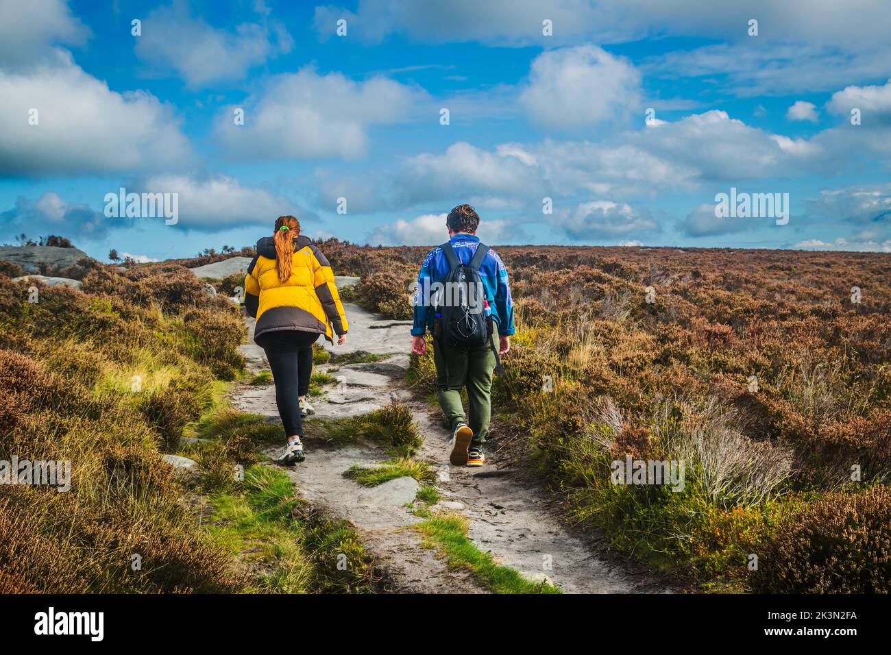24.09.2022 Burbage, Sheffield, Female hill walkers in outdoor clothing stridding across gritstone moors in the Peak district Stock Photo