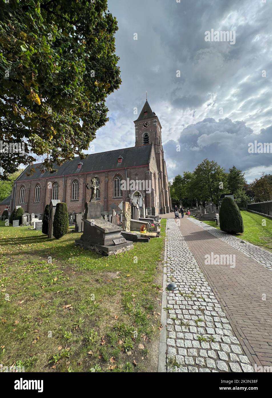 Bellem , East-Flandres, 09 18 2022 : A wide angle view on the catholic church with a walkway along the cemetary Stock Photo