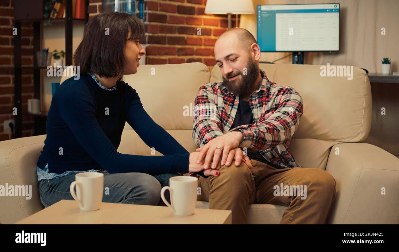 Husband and wife solving marriage problems at therapy session meeting, holding hands and enjoying relationship reconciliation. Making peace at appointment with psychotherapist in office. Stock Photo