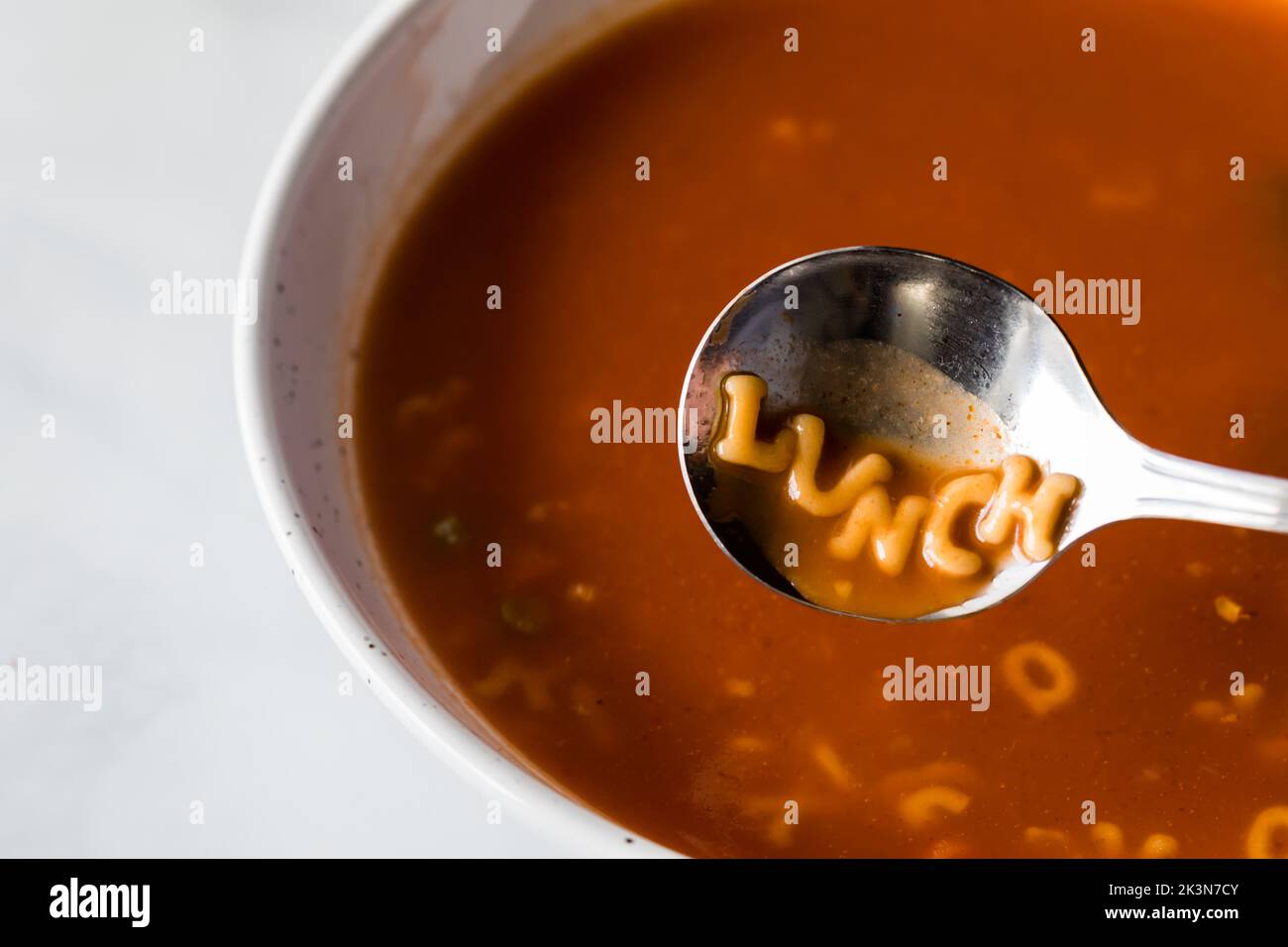 A bowl of alphabet tomato soup with the word lunch spelled out in the