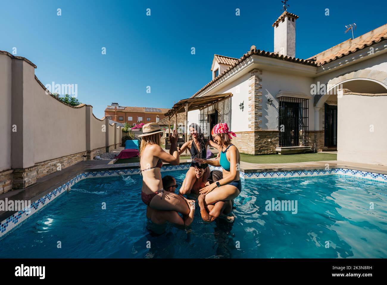 3 women on the shoulders of 3 men in a swimming pool Stock Photo
