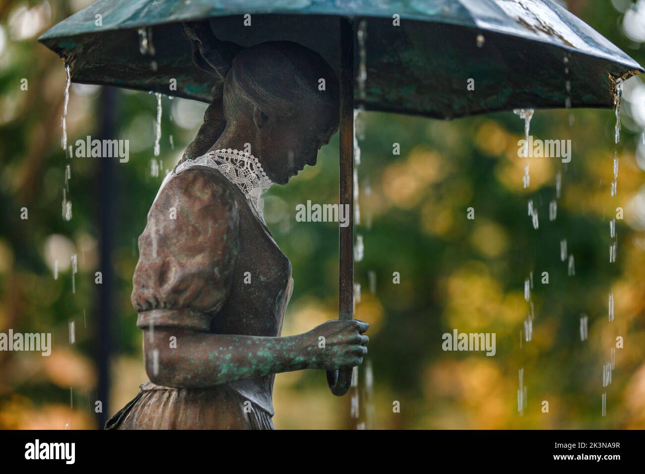 Rain falls on statue of a woman with umbrella and lace collar Stock Photo