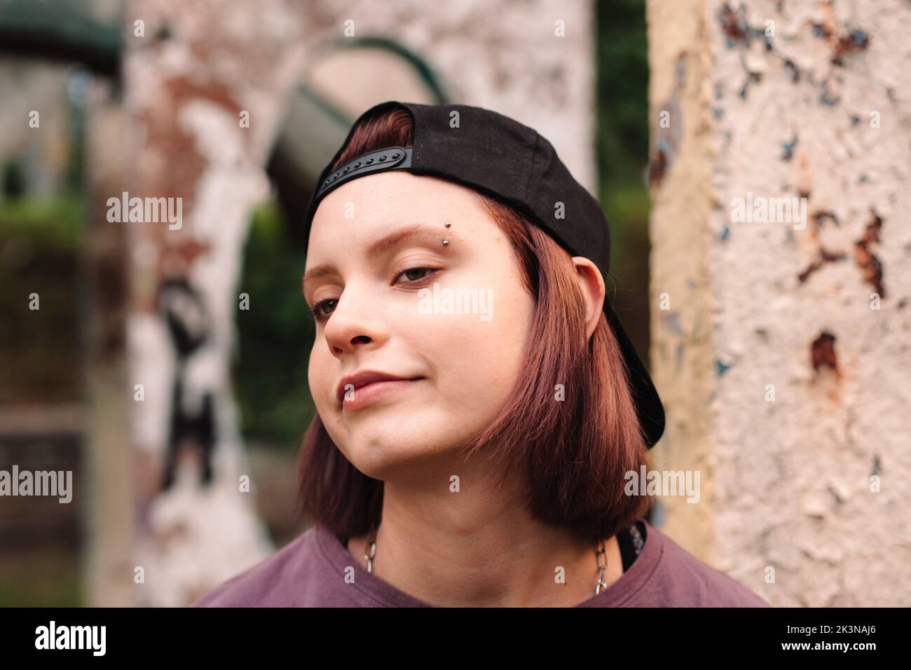 Portrait of punk teenage girl with pierced eyebrow in cap backwards