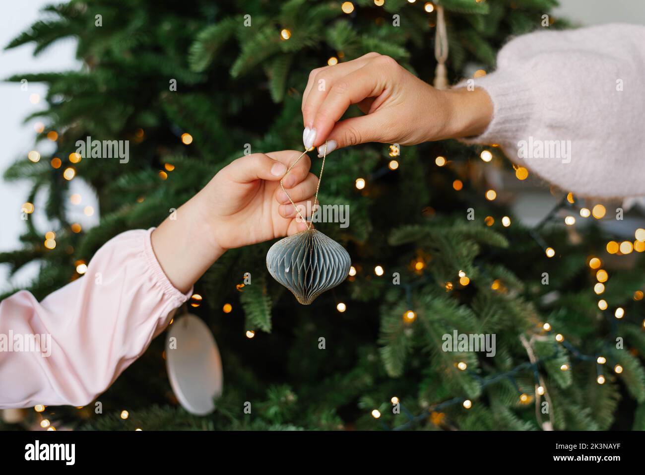 Mom hands passing a Christmas toy to daughter for decoration Stock Photo