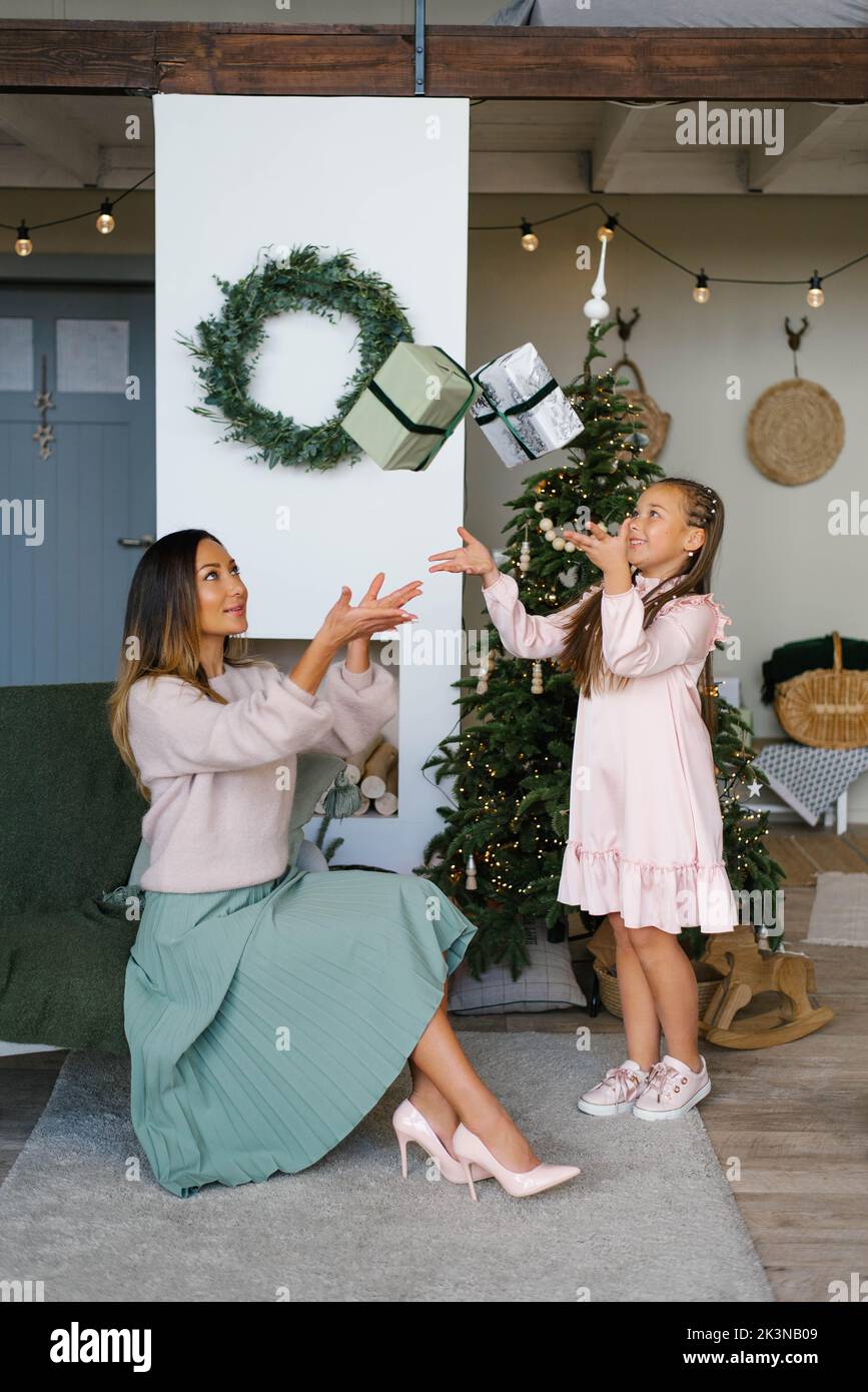 Happy mom and daughter have fun at the Christmas tree Stock Photo