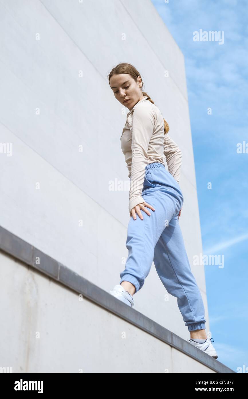 Young girl in a blue pants stretching and dancing against blue sky Stock Photo