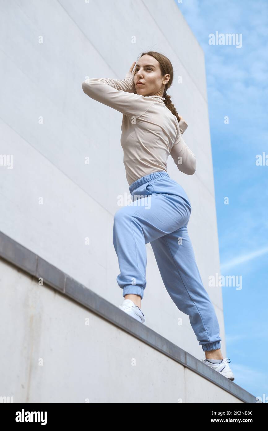 Young girl in a blue pants stretching and dancing against blue sky Stock Photo