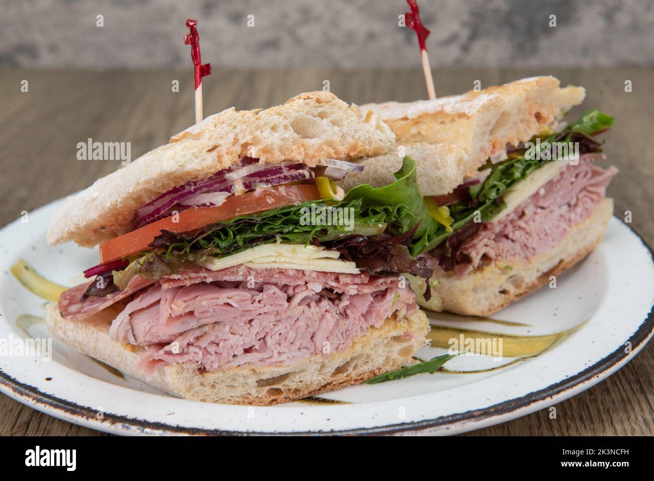 Loaded Italian sub sandwich is thick with ham, cheese, pepperoni, tomato, and onion on a freshly baked roll. Stock Photo