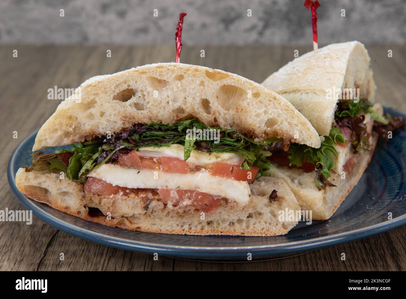 Vegan option sandwich with mozarella cheese, tomato, and savoy greens on a ciabatta bread bun