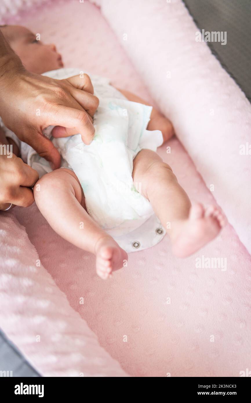 Selective focus of man's hands placing the diaper on a baby in his crib