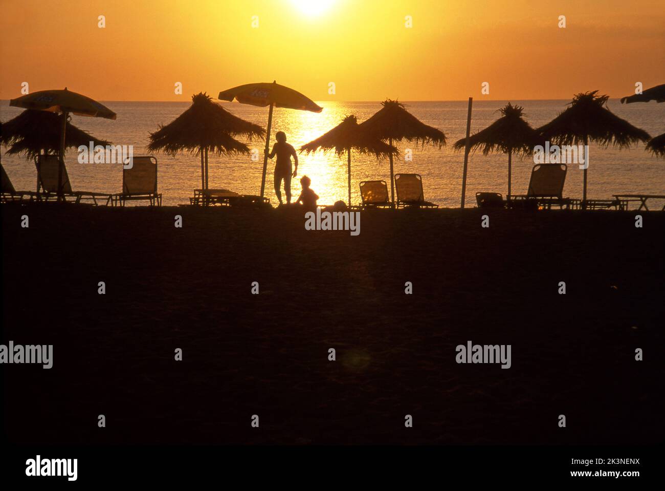 People under an umbrella on a beach on the Greek Island of Crete in the Aegean Sea. Stock Photo