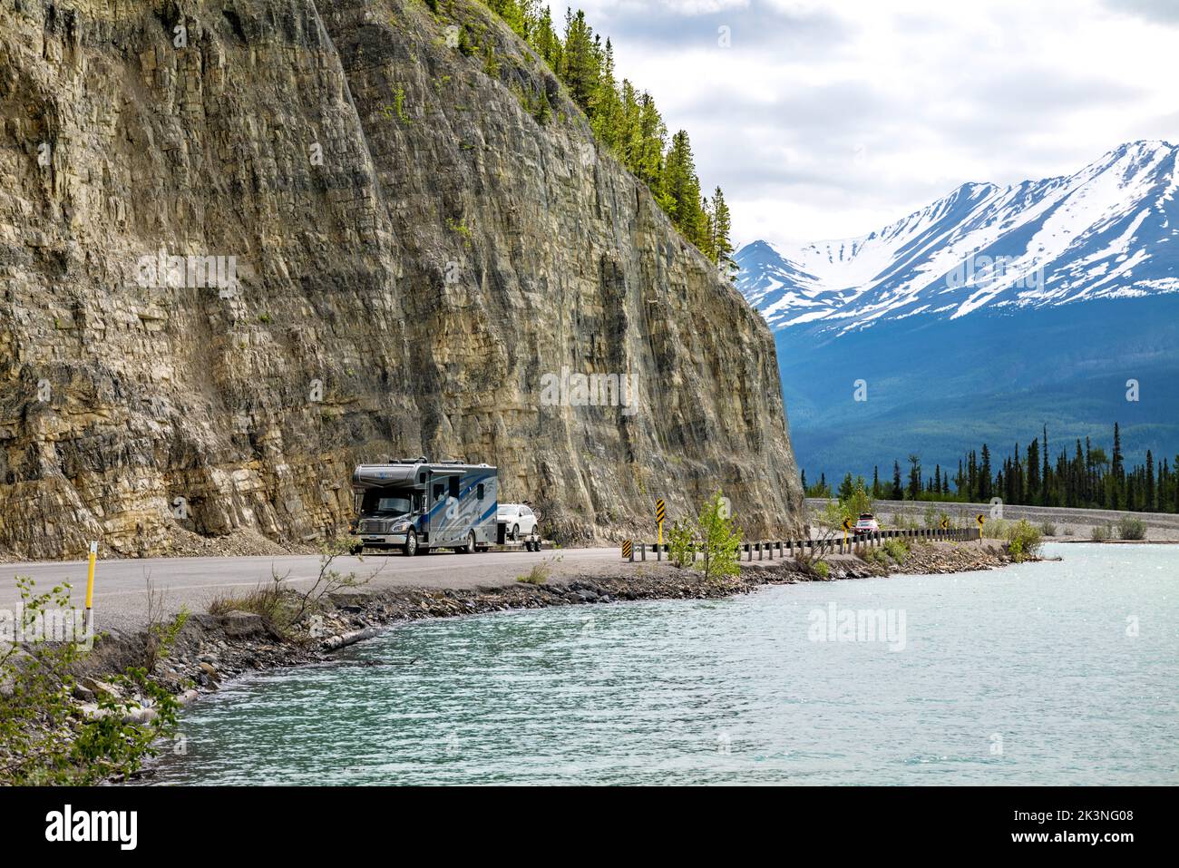 Camper travels the Alaska Highway along Muncho Lake, surrounded by Canadian Rocky Mountains; British Columbia; Canada Stock Photo