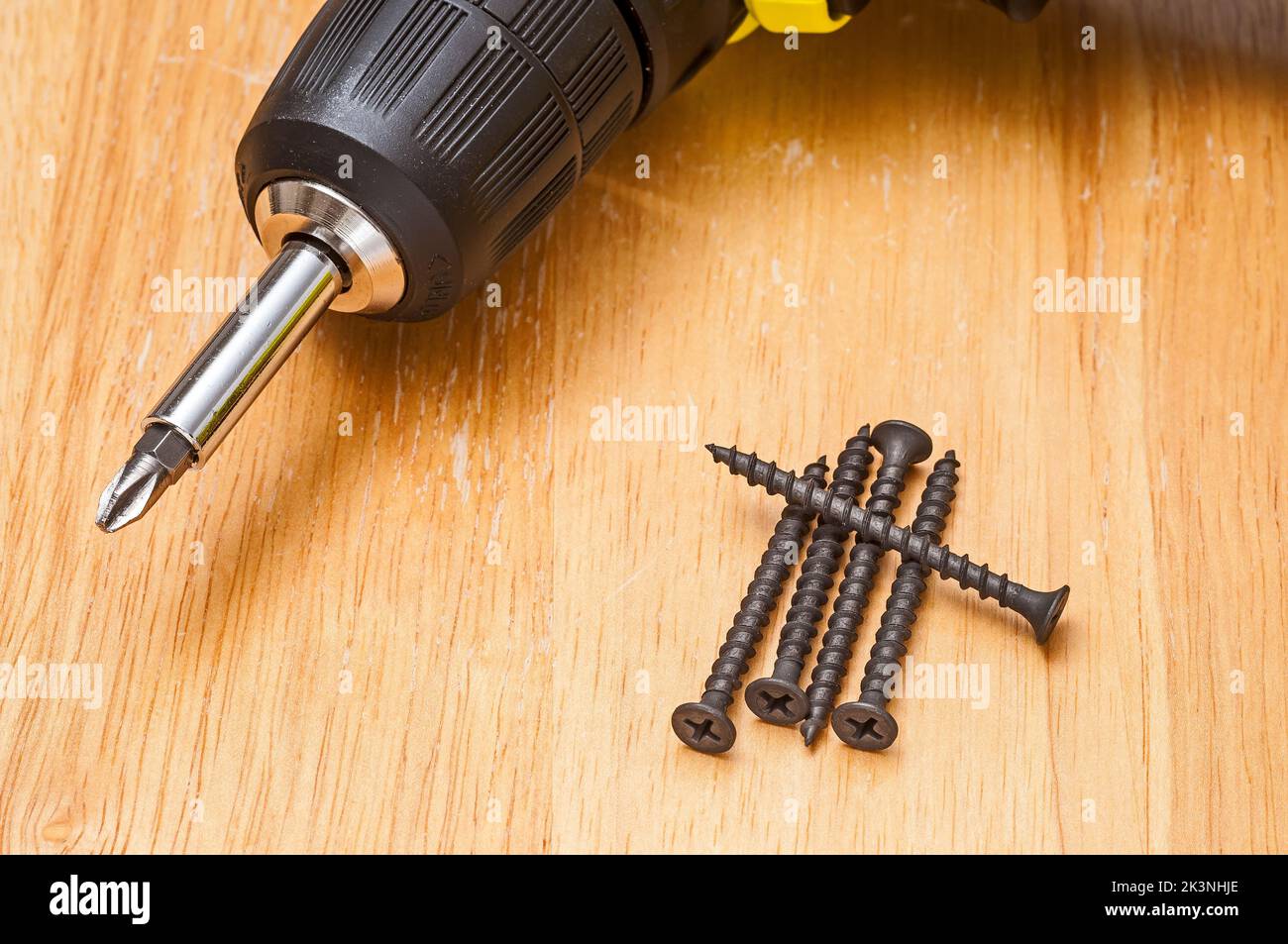 Five black drywall screws and an electric drill or driver Stock Photo