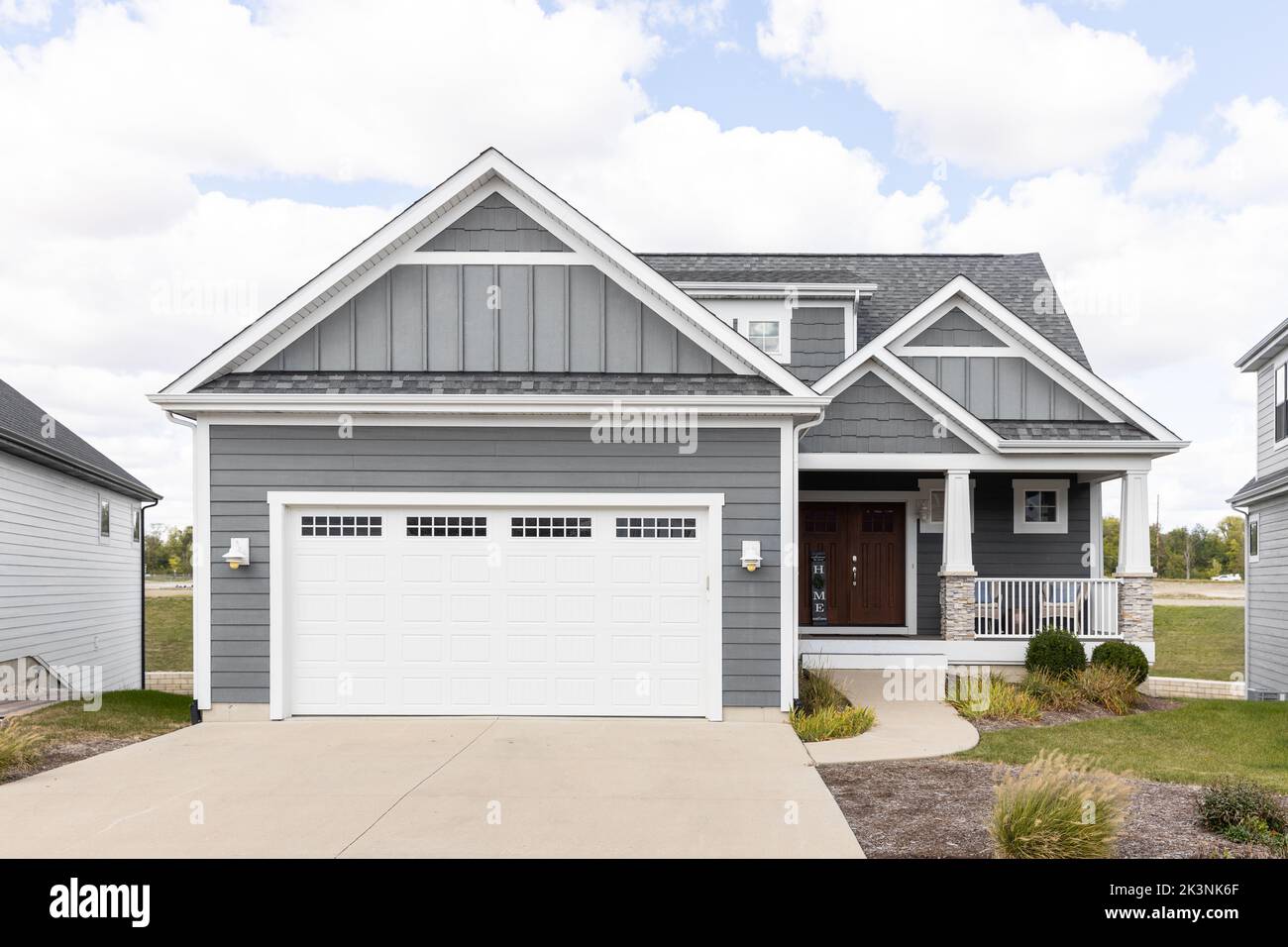 A new, grey home with horizontal and vertical siding, white garage door