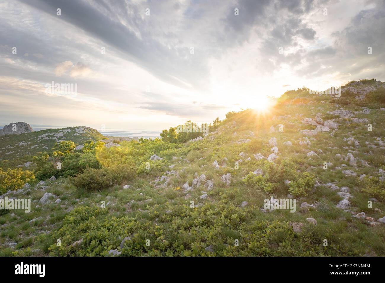 A landscape view of the Velebit Mountain range with the sun shining in the background Stock Photo