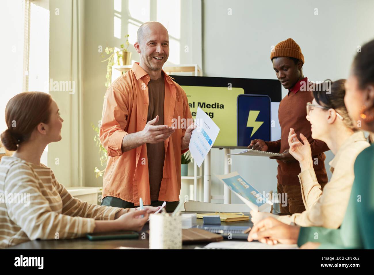 Portrait of creative team meeting in office with focus on smiling businessman giving marketing presentation Stock Photo