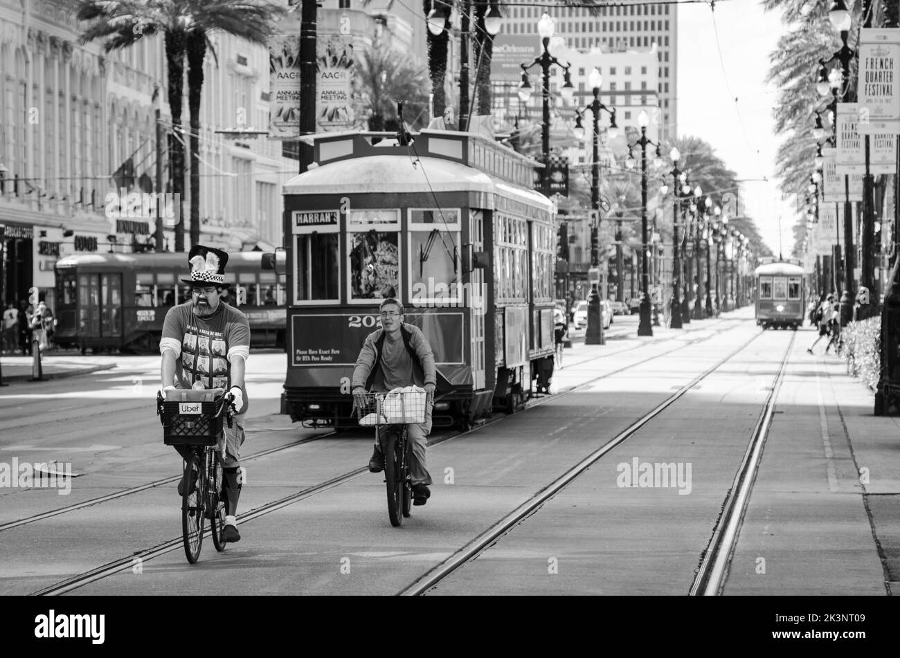 Cyclists riding along Canal Street in New Orleans, Louisiana in front of a street car. Stock Photo