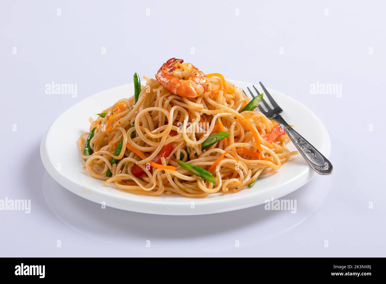 Schezwan Noodles or Szechwan vegetable Hakka Noodles or chow mein is a popular Indo-Chinese recipes, served in a bowl or plate with wooden chopsticks Stock Photo