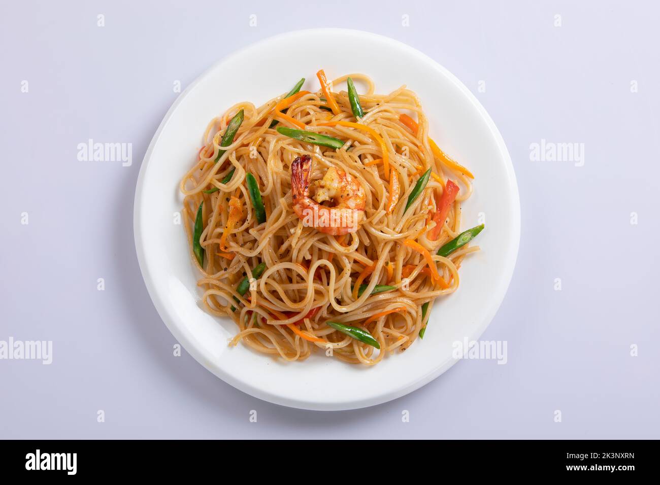 Schezwan Noodles or Szechwan vegetable Hakka Noodles or chow mein is a popular Indo-Chinese recipes, served in a bowl or plate with wooden chopsticks Stock Photo