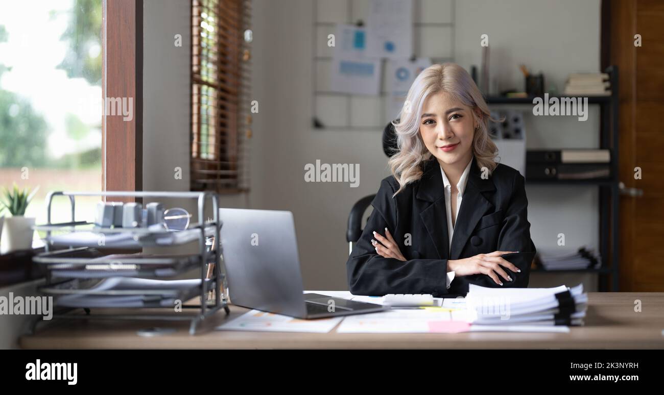 Portrait of young asian business woman sitting arms crossed in modern office. Stock Photo