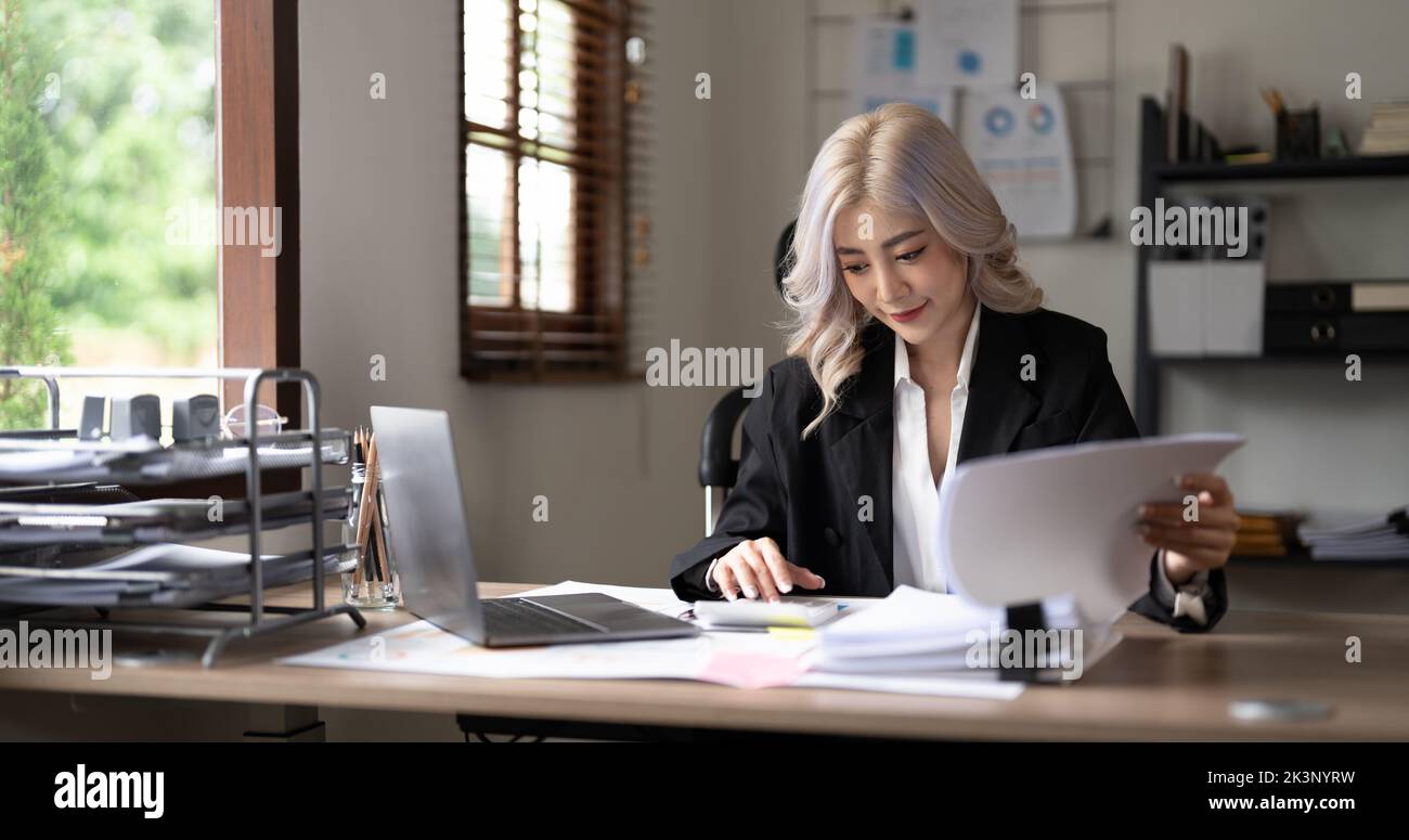 businesswoman working on desk office with using a calculator to calculate the numbers, finance accounting concept. Stock Photo